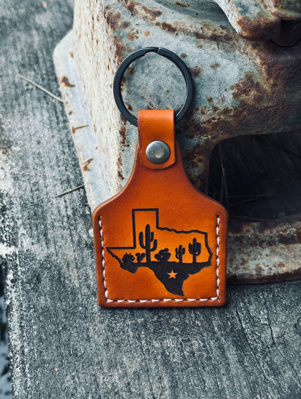 Brown leather keychain with Texas outline and cactus design on a textured surface