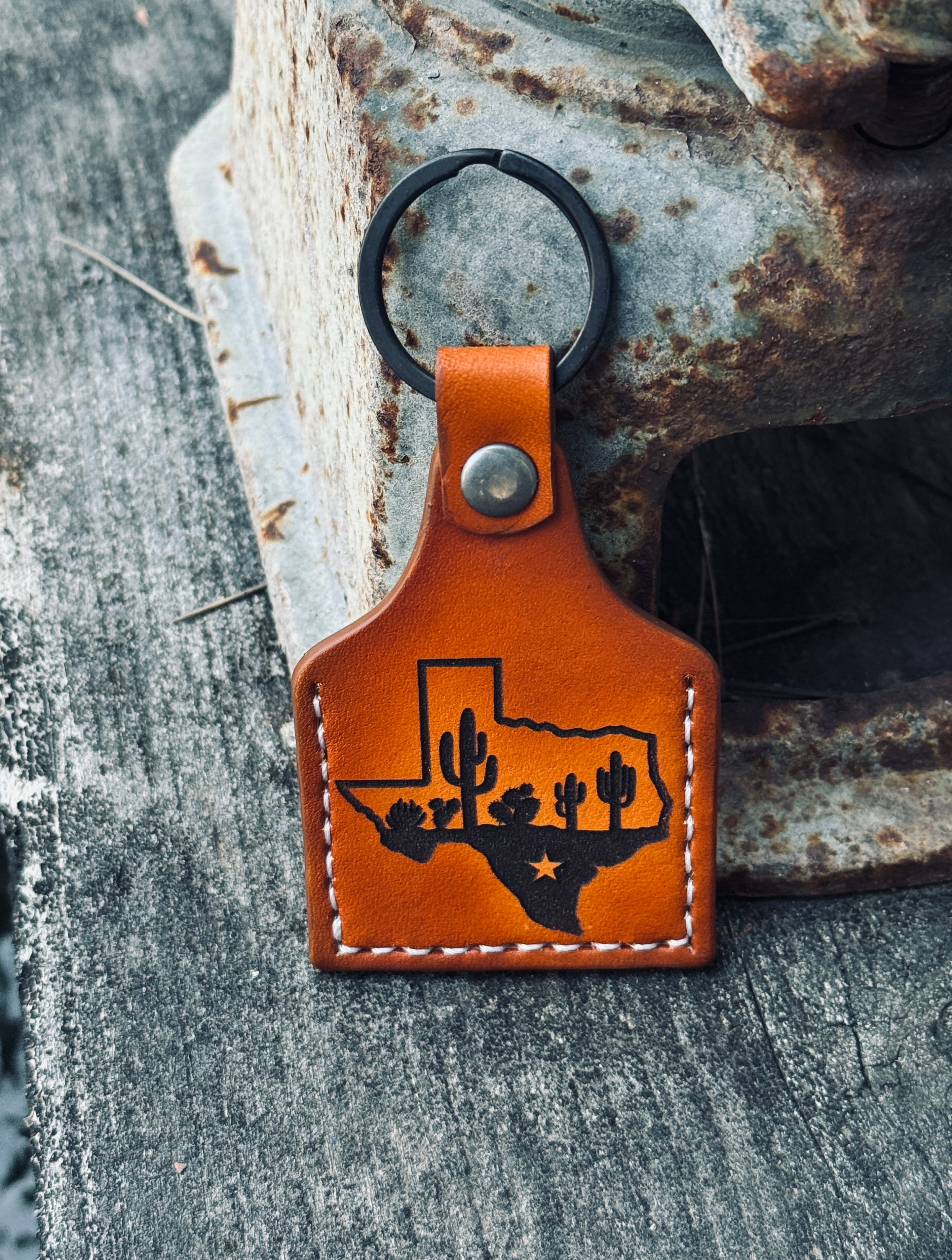 Brown leather keychain with Texas outline and cactus design on a textured surface