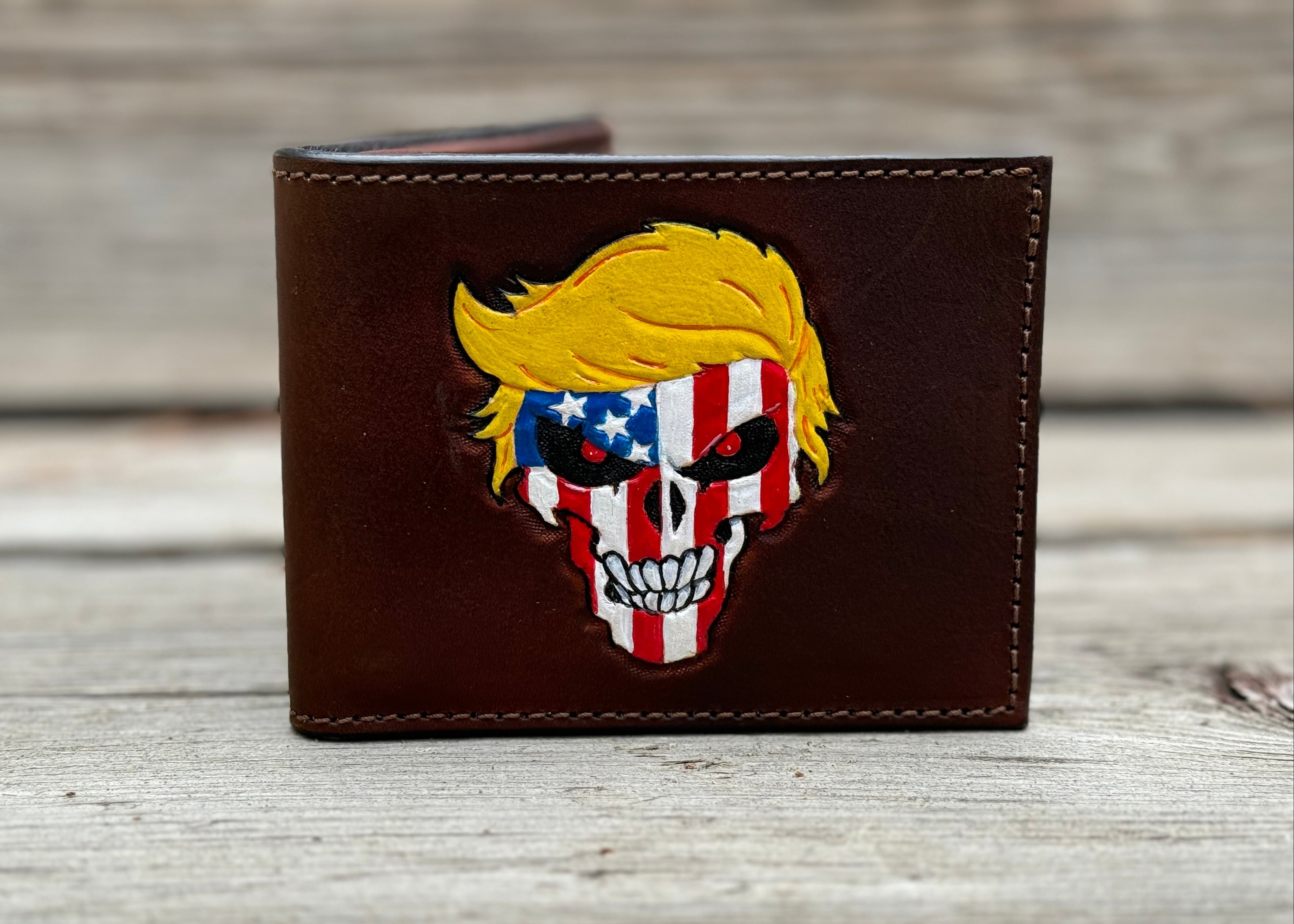 Brown leather wallet with a Trumpisher skull design featuring an American flag on a wooden surface