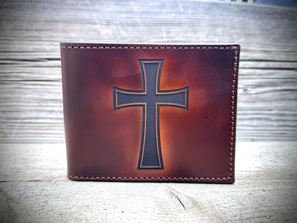 Brown leather wallet with a cross design on a wooden surface