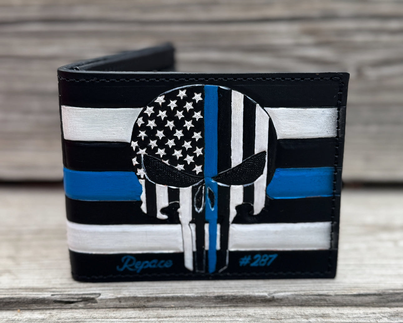 Wallet with American flag design and Punisher Blue Lives Matter skull emblem on a wooden surface