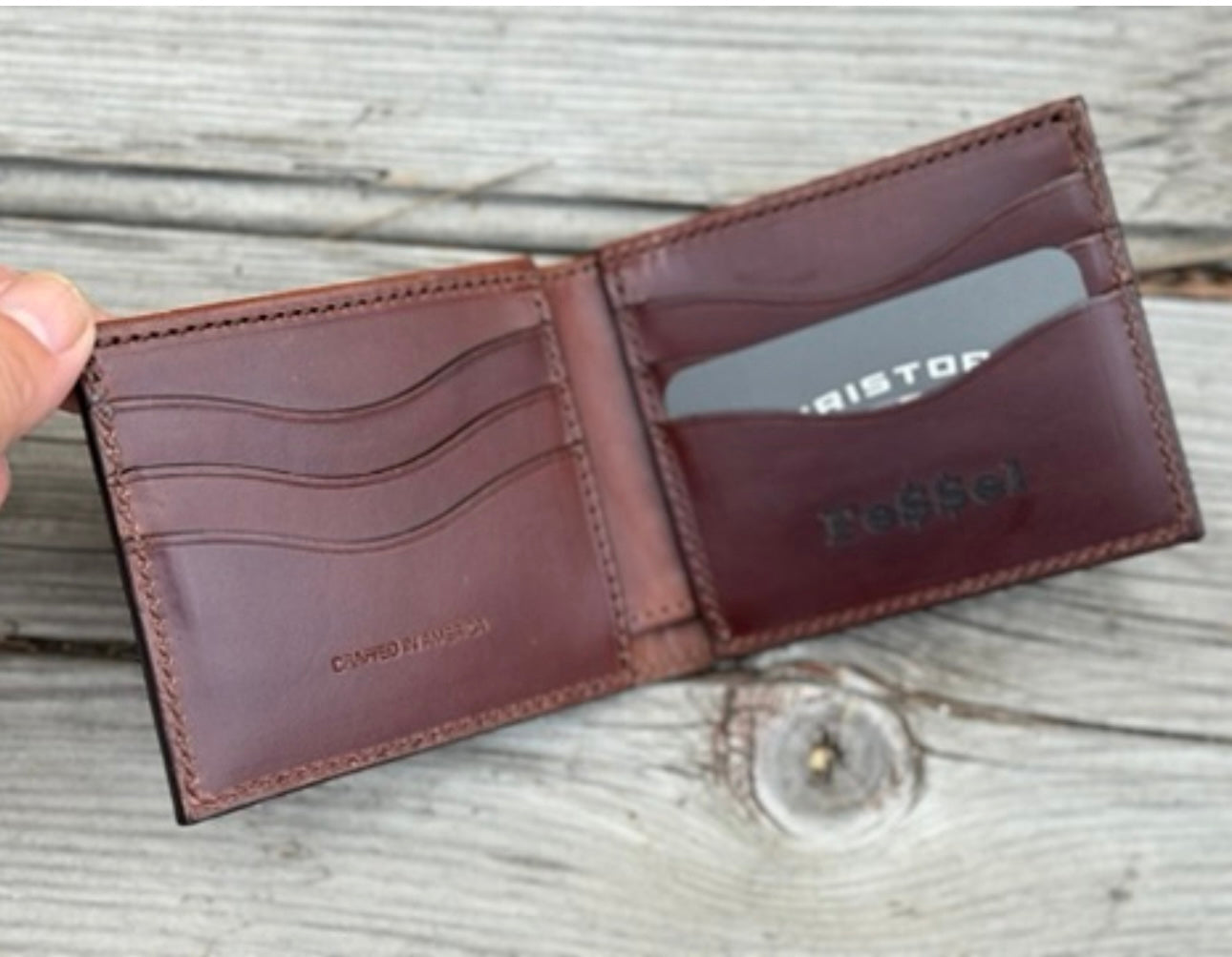 Brown leather wallet with visible branding on a wooden surface