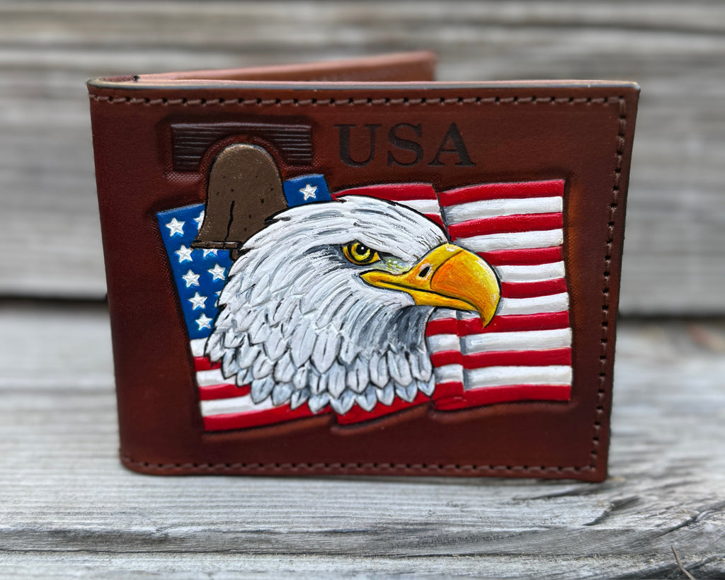 Brown leather wallet with an eagle and American flag design on a wooden surface