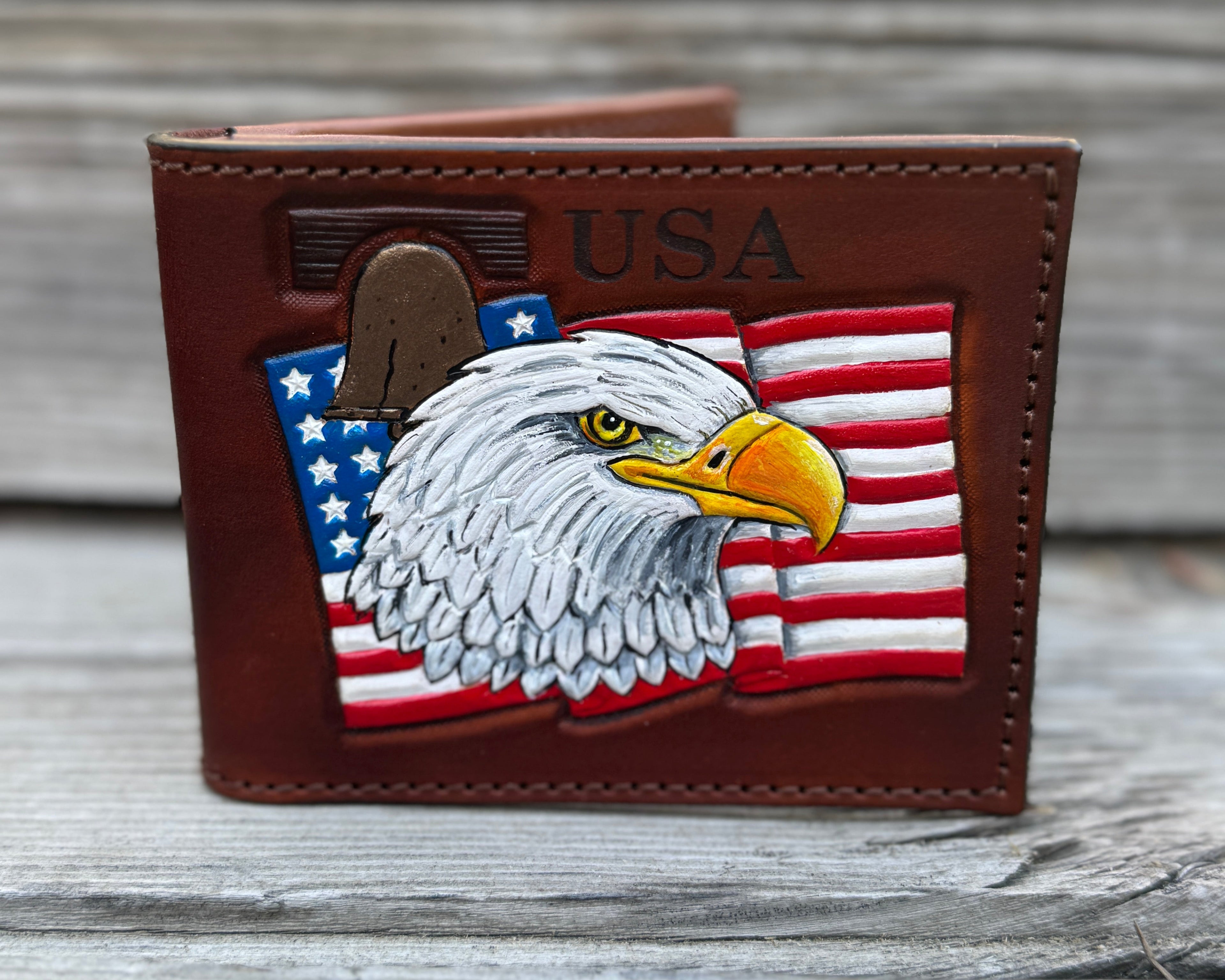 Brown leather wallet with an eagle and American flag design on a wooden surface